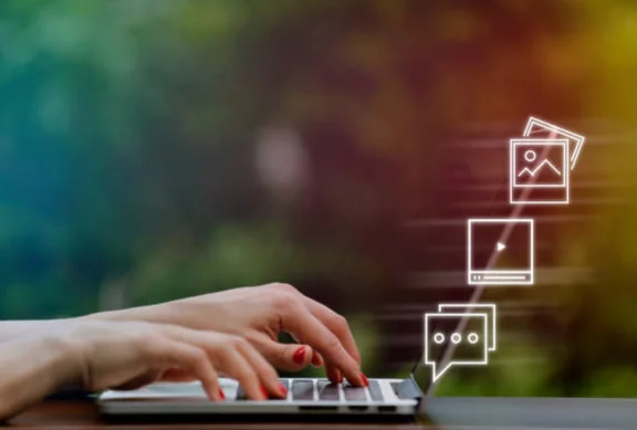 A person typing on a laptop with icons from the screen, representing top consultant service