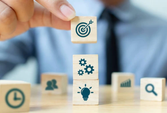 A person holding wooden blocks with icons on them, representing management and mentoring services.