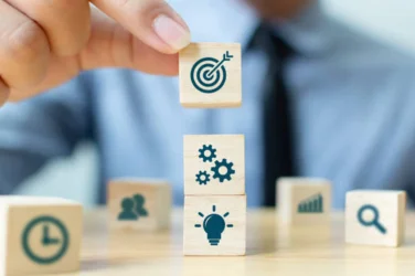 A person holding wooden blocks with icons on them, representing various concepts or ideas