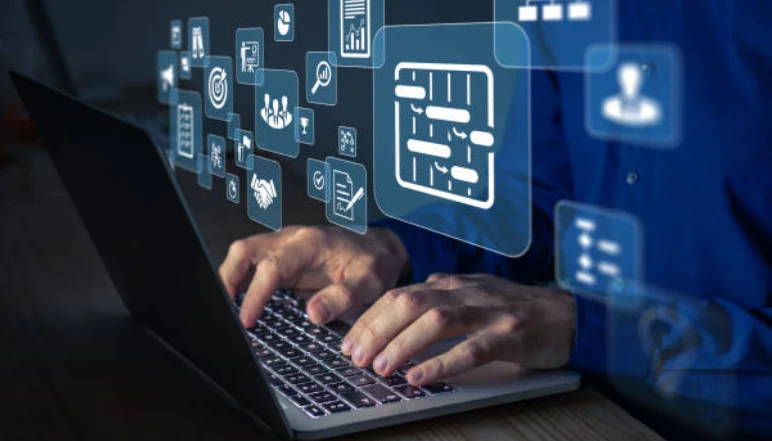 A person typing on a laptop with various icons on the screen from the Project Management Office.